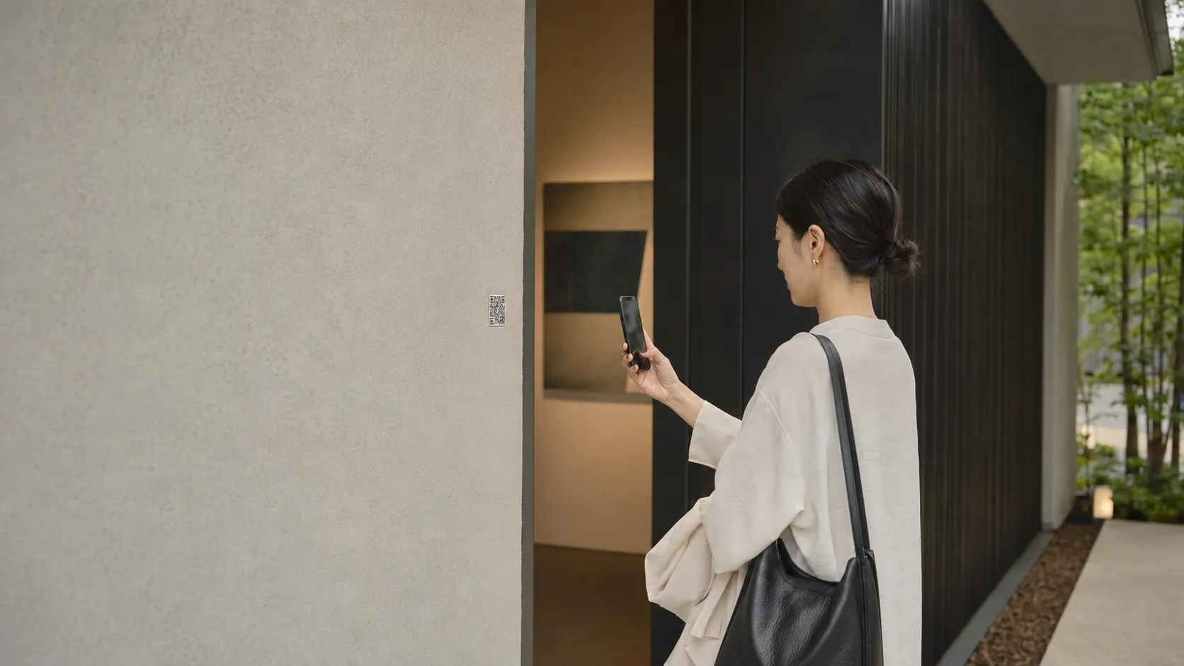 作品を鑑賞しながらスマートフォンで作家情報を確認する来場者